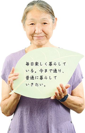 「毎日楽しく暮らしている。今まで通り、普通に暮らしていきたい。」と書かれたリーフを手に持つ澤田佐紀子さんの写真
