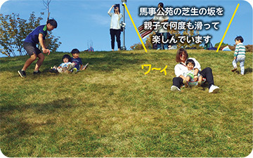 馬事公苑の芝生の坂を親子で滑る様子